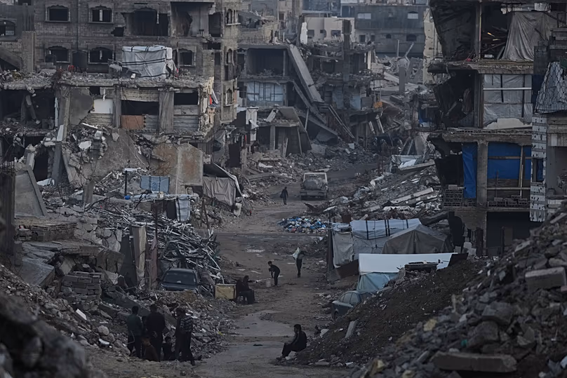 Palesztinok sétálnak az izraeli légi és földi hadműveletek során lerombolt épületek között Gázában, 2026. január 6.