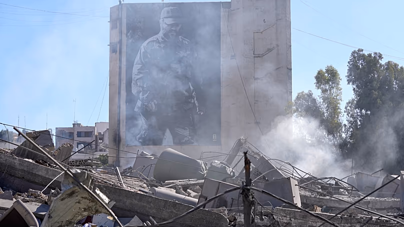 Egy plakáton a Hezbollah néhai katonai parancsnoka, Imad Mughniyeh látható egy lerombolt épület mögött, amelyet egy izraeli légicsapás érte Nabatiyehben, 2026. március 5.