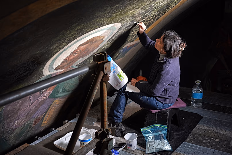 Celeste Parrendo műemlékvédelmi technikus az egyesült államokbeli Millvale-i Szent Miklós horvát katolikus templom falfestményeinek egy szakaszán dolgozik, 2025-ben.