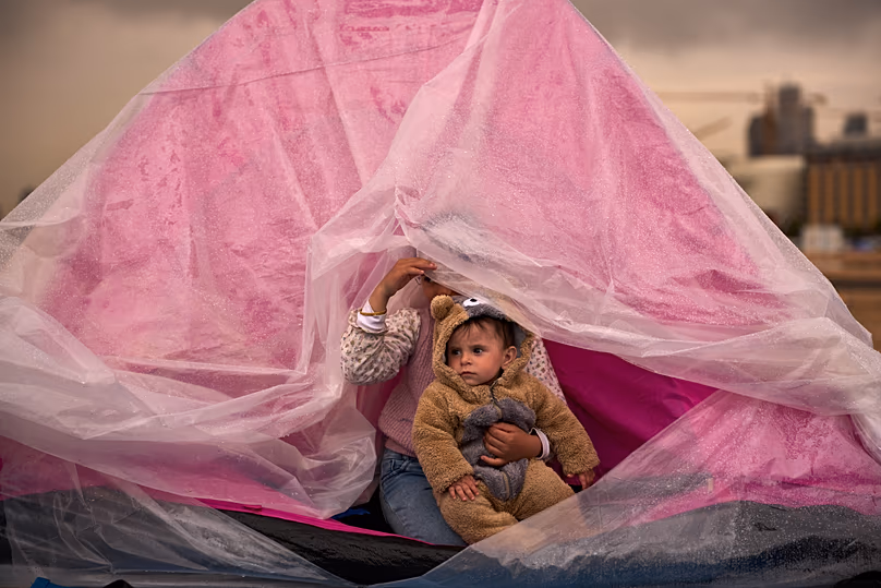 Yasmin a bátyját, Alit tartja fogva Bejrút déli külvárosából, Dahiyehből, amint egy sátorban mennek az eső elől Bejrút partja mentén, 2026. március 26-án.