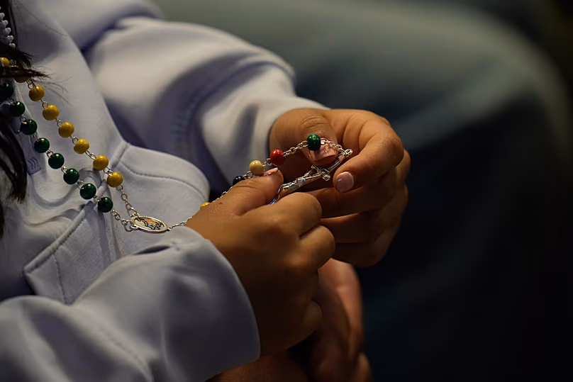A woman holds a rosary as she attends a vigil for peace led by Pope Leo XIV inside St Peter's Basilica at the Vatican, 11 April 2026